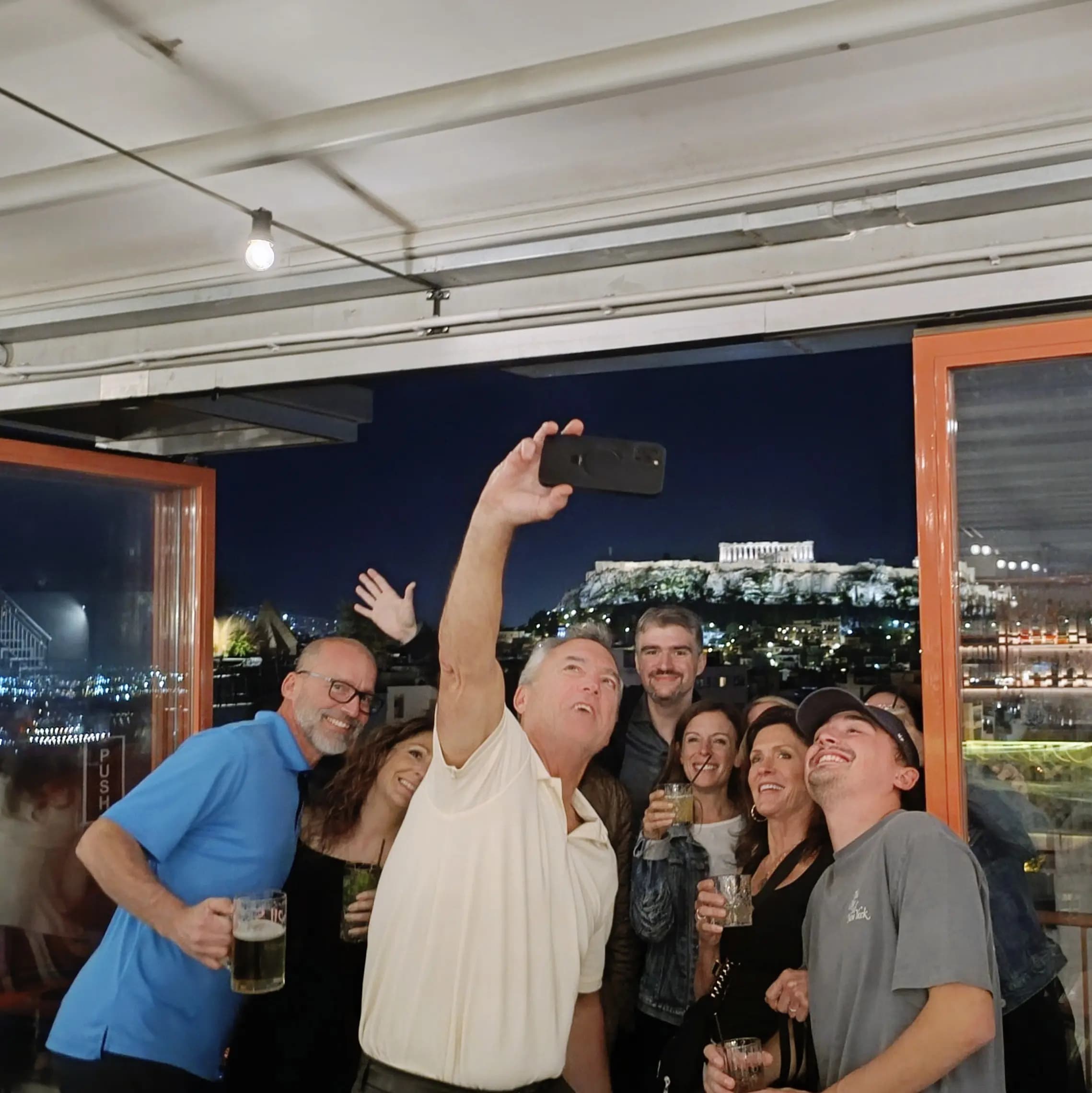 Travelers taking selfie at exclusive Athens rooftop bar venue overlooking the city